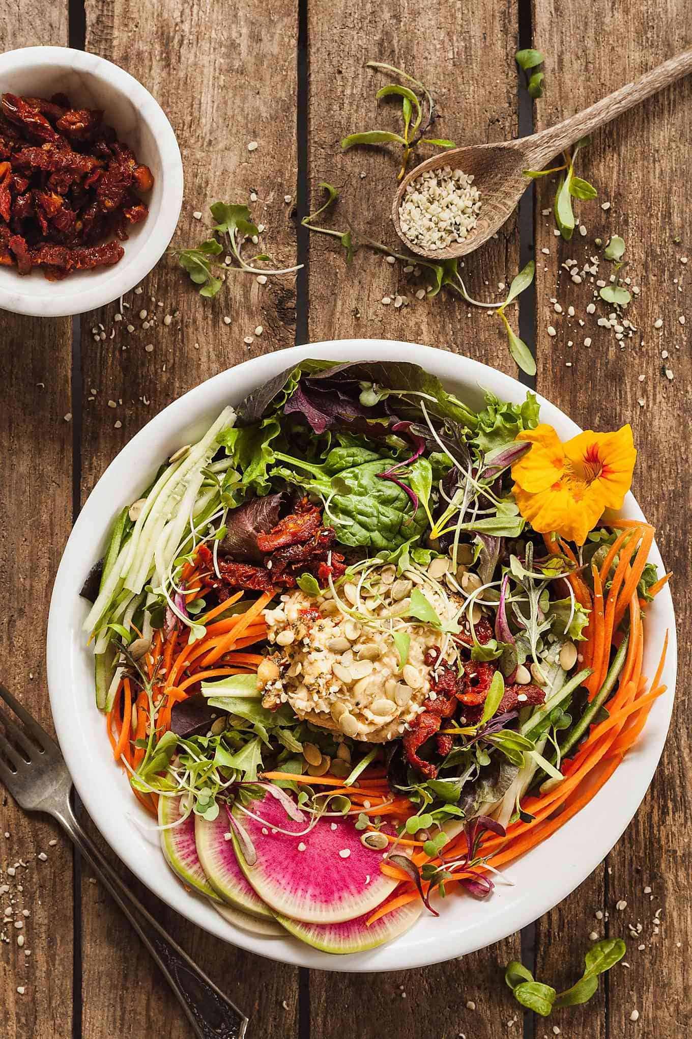 Fresh vegan salad with colorful vegetables and hummus